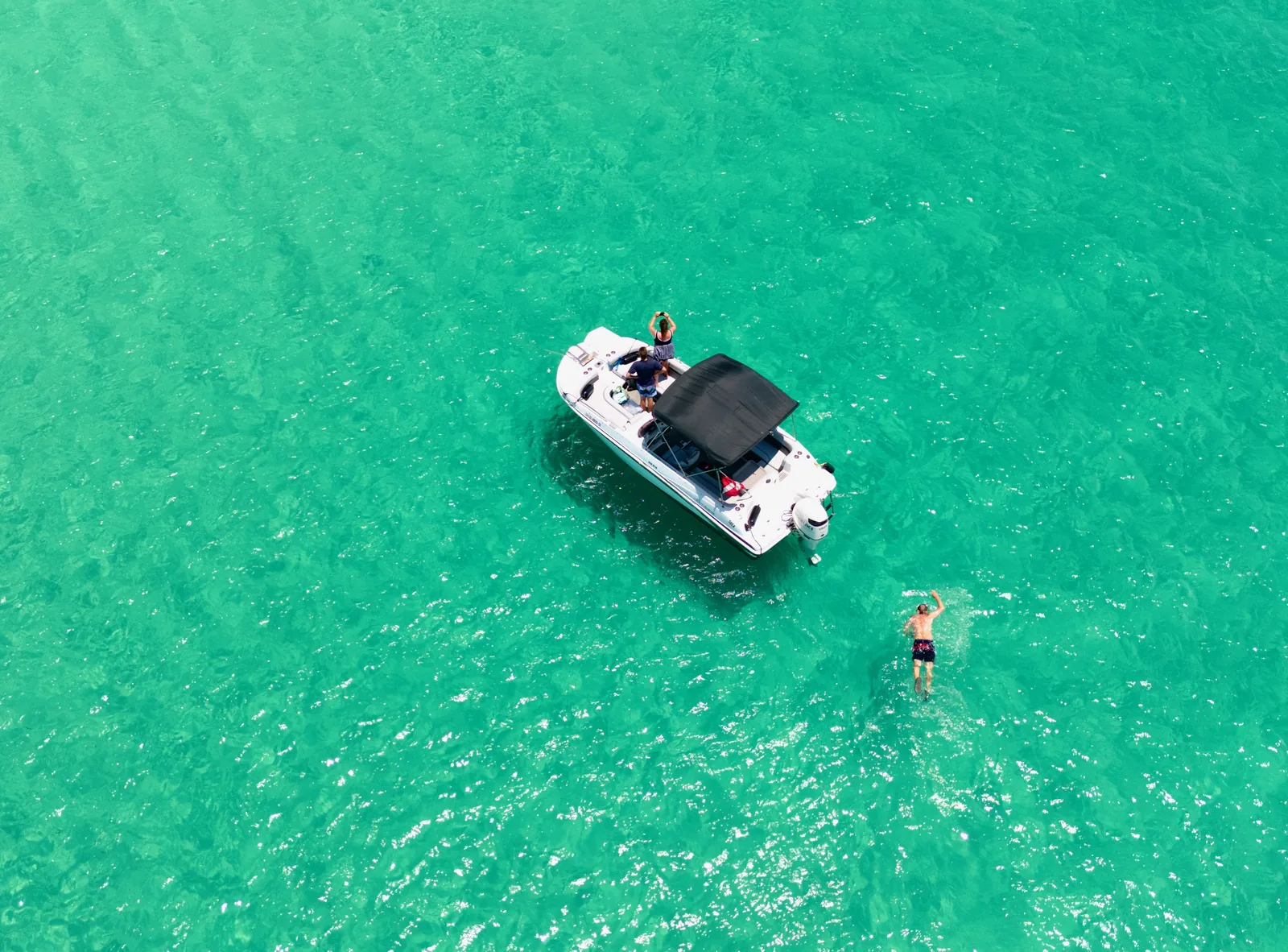 Aerial of boat on emerald Gulf water with swimmer