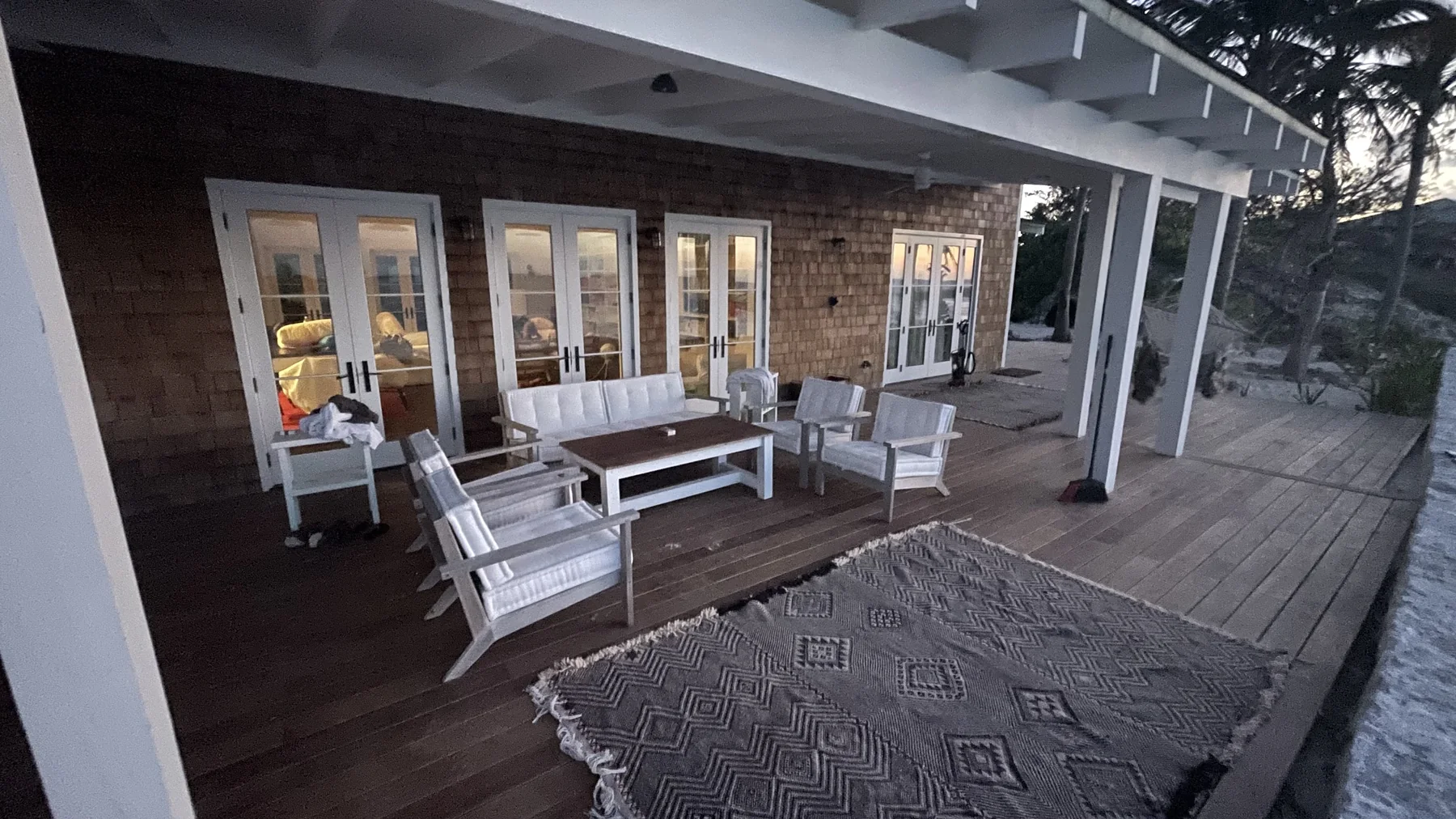 White outdoor seating with rug and french doors at twilight