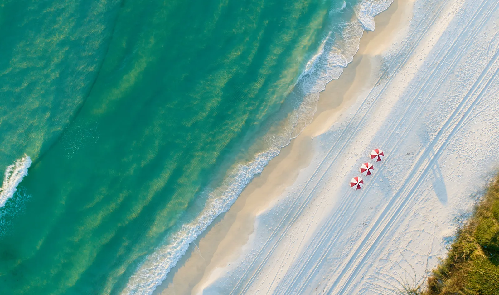 Aerial of red beach umbrellas on white sand